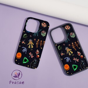 May include: Two black phone cases featuring a repeating pattern of cartoon characters, stars, and other whimsical elements. The cases have a dark background and a variety of colourful illustrations. The cases are on a purple surface.