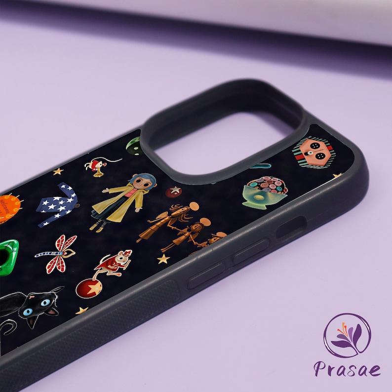 May include: Black phone case with a dark background adorned with colourful cartoon illustrations. The design includes a girl in a yellow coat, a black cat, and other whimsical characters. The case has a black border and a logo in the bottom right corner.