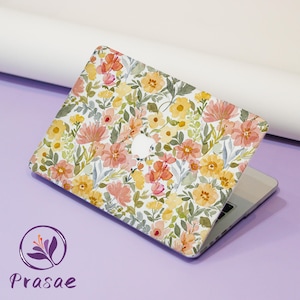 May include: A laptop with a floral design case. The case features a pattern of yellow, orange, and pink flowers with green leaves on a white background. The laptop is open, revealing the keyboard and screen.