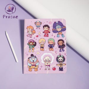 Könnte beinhalten: Ein rechteckiges Notizbuch mit einem hellvioletten Einband, der ein weißes Gittermuster und zahlreiche bunte Cartoon-Charakter-Illustrationen aufweist. Die Figuren sind im Chibi-Stil dargestellt, ergänzt durch kleine Symbole wie Herzen, Sterne und einen Apfel.