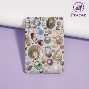 May include: A rectangular phone case featuring a collage of iridescent pearls, seashells, and various shapes in shades of white, beige, and brown. The design includes a variety of textures and colors, creating a detailed and visually appealing pattern.