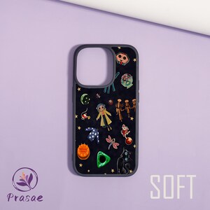 May include: A black phone case with a dark grey border, decorated with cartoon characters, stars, and other whimsical elements. The word "SOFT" is printed in white on the bottom right. The case has cutouts for the camera and buttons.