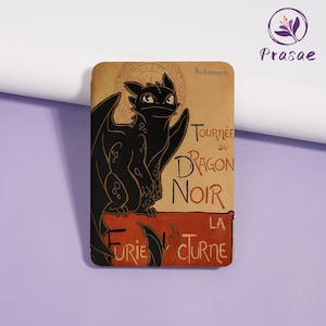 May include: A rectangular, tan-colored magnet featuring a black dragon illustration with the text "Tournée du Dragon Noir" in white and red. The dragon has large wings and is set against a vintage-style background.
