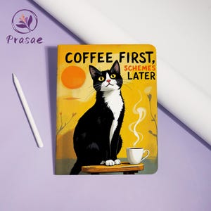 Könnte beinhalten: Ein rechteckiges Notizbuch mit einem schwarz-weißen Katzenmotiv, die auf einem Holzhocker neben einer dampfenden Kaffeetasse sitzt. Der gelbe Hintergrund zeigt eine Sonne und den Text COFFEE FIRST, SCHEMES LATER. Ein weißer Eingabestift liegt links.