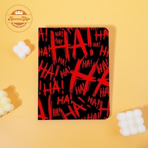 May include: Black notebook with a repeating red "HA!" design. The notebook has rounded corners and a smooth cover. The text is in a bold, graffiti-style font. The notebook is a unique gift.