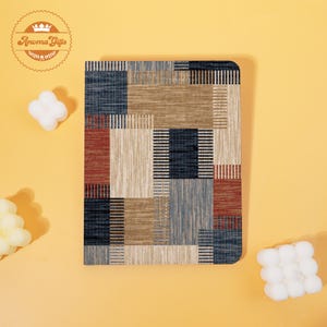 May include: A rectangular notebook with a geometric pattern in shades of blue, beige, and red. The notebook has rounded corners and is set against a yellow background. The logo "Aroma Gifts" is in the upper left corner.