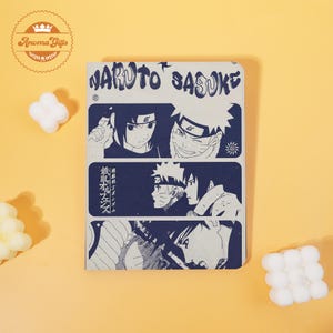 May include: A notebook featuring a blue and white graphic design with the text "NARUTO SASUKE". The notebook has illustrations of anime characters. The notebook is on a yellow background.
