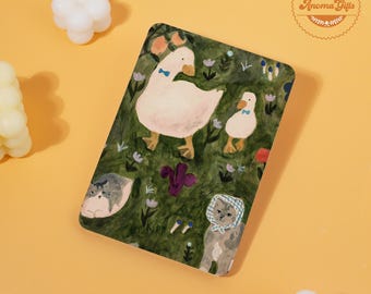 May include: A rectangular decorative item featuring a whimsical illustration of two geese and two cats in a garden setting. The geese wear blue bow ties, and the cats are wearing bonnets. The background is a green field with flowers.