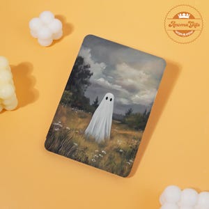 May include: A rectangular art print featuring a white ghost in a field with a cloudy sky background. The ghost has two black eyes. The print has a matte finish and is likely a decorative item.