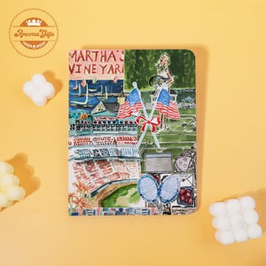 May include: A rectangular decorative item with a colorful illustration featuring the text "MARTHA'S VINEYARD". The artwork includes American flags, a tennis scene, and a stadium, with a nautical theme. The item has a light yellow background.