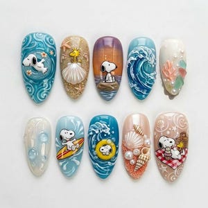 May include: A set of ten intricately designed nail art pieces. Each nail features a different summer-themed design, including Snoopy characters, seashells, waves, and beach scenes. The color palette includes blues, tans, and whites, creating a cohesive and playful aesthetic.