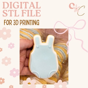 May include: A light blue onesie-shaped biscuit with white trim and two small buttons. The biscuit is held in a hand and is part of a set of biscuits. The image also contains the text "DIGITAL STL FILE FOR 3D PRINTING".