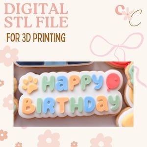 Op de afbeelding: Een digitaal STL-bestand voor 3D-printen, met een versierd koekje met de woorden "Happy Birthday" in kleurrijk glazuur. Het koekje bevat een pootafdruk en een ballon.