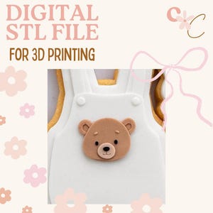 May include: A digital STL file for 3D printing, showcasing a white onesie design with a brown teddy bear face. The text "DIGITAL STL FILE FOR 3D PRINTING" is in pink. The background is a soft beige with pink floral accents.