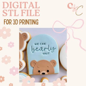 May include: Digital STL file for 3D printing. A light blue cookie with a bear face and the words "We can bearly wait" in black script is shown. Other bear-faced cookies are also visible in the image.
