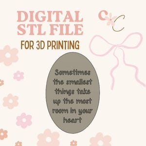May include: A digital STL file for 3D printing featuring a taupe oval plaque with the text 'Sometimes the smallest things take up the most room in your heart'. The background is light pink with scattered light pink flowers and a pink ribbon graphic.