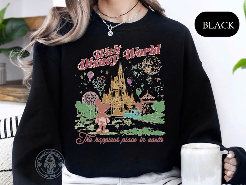 Puede incluir: Sudadera negra con un gr&aacute;fico colorido de Walt Disney World, que incluye un castillo, fuegos artificiales y globos. El texto "Walt Disney World" y "The happiest place in earth" est&aacute; en una fuente retro.
