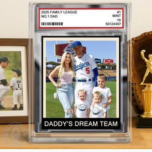 May include: A baseball card encased in a clear protective case. The card features a family photo with the text "2025 FAMILY LEAGUE NO.1 DAD" and "DADDY'S DREAM TEAM". The card is graded "MINT 10".