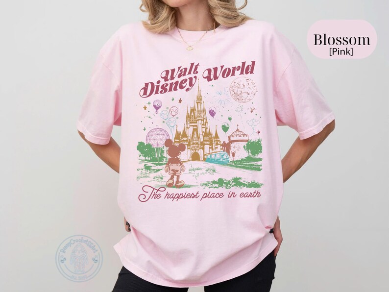 Puede incluir: Camiseta rosa claro con un dise&ntilde;o de Walt Disney World, con un castillo, Mickey Mouse y globos. El texto dice "Walt Disney World" y "The happiest place in earth."