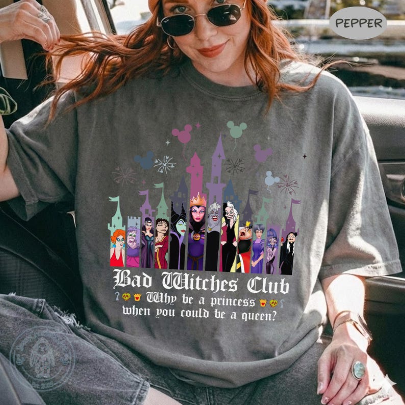 Puede incluir: Camiseta gris con un dise&ntilde;o gr&aacute;fico de villanos de Disney frente a una silueta de castillo. El texto dice "Bad Witches Club" y "&iquest;Por qu&eacute; ser una princesa cuando puedes ser una reina?"