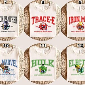 May include: Off-white t-shirts with various superhero designs. Each shirt features a different character name in bold lettering, along with a graphic and the text "Spidey and His Amazing Friends". Characters include Black Panther, Trace-E, Iron Man, Ms. Marvel, Hulk, and Electro.