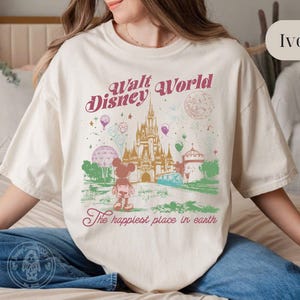 Puede incluir: Camiseta de color marfil con un gr&aacute;fico colorido de Walt Disney World. El dise&ntilde;o incluye un castillo, Mickey Mouse y el texto "Walt Disney World" y "The happiest place in earth."
