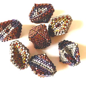 May include: Seven small, geometrically shaped beaded ornaments in shades of brown, purple, and silver. The ornaments are made of small, square beads and have a slightly iridescent finish.