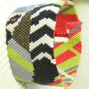 May include: A colourful beaded bracelet with a chevron pattern in shades of black, white, grey, green, and red.