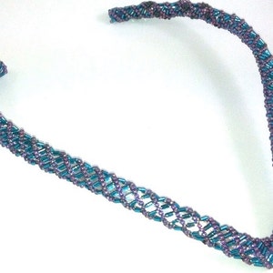 Puede incluir: Un collar de cuentas de color turquesa y morado con un diseño en forma de V.