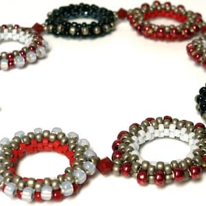 May include: A beaded bracelet with alternating circles of red, white, black, and silver beads. The bracelet has a toggle clasp.