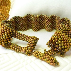 May include: A gold and brown beaded bracelet with a wavy design. The bracelet has a clasp closure.