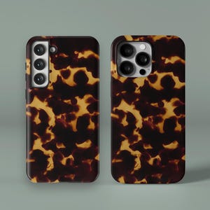 May include: Two phone cases with a tortoiseshell pattern. The cases are brown and tan with a glossy finish. One case has a triple-lens camera, and the other has a multi-lens camera.