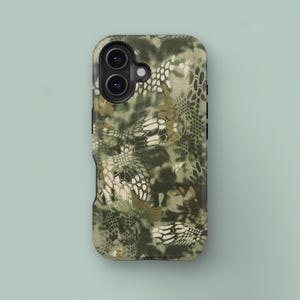 May include: A phone case featuring a camouflage design in green, brown, and white hues. The case has a textured pattern and a black edge. The camera lenses are visible at the top.