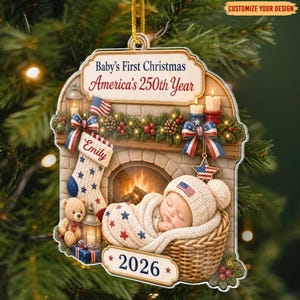 May include: A decorative Christmas ornament featuring a fireplace scene with a baby in a basket, a stocking labeled Emily, and text reading Baby's First Christmas America's 250th Year and 2026. The design includes patriotic stars, stripes, and candles.