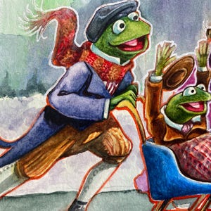 Puede incluir: Ilustración en acuarela de Kermit la Rana en una escena invernal. Kermit lleva un abrigo azul, calzones marrones y una bufanda roja. Otra rana está en un trineo azul, saludando con un sombrero.