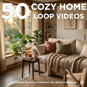 May include: A cozy living room scene with a cream-colored sofa, throw pillows, and a knitted blanket. A small wooden table holds a candle and a mug. The text "50 COZY HOME LOOP VIDEOS" is displayed. Plants and a window with natural light are also visible.