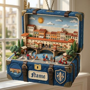 May include: A blue suitcase diorama featuring a miniature 3D scene of a bridge with buildings, small figures, trees, and a red scooter. The exterior has brown leather straps, a gold lock, a circular bridge patch, and a label with the text Name.