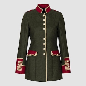 Puede incluir: Una chaqueta de estilo militar verde oscuro con ribetes dorados y detalles rojos. La chaqueta tiene un cuello alto, mangas largas y cierre de botones.