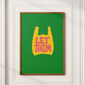 May include: A framed art print with a green backdrop and a yellow shopping bag design. The pink text "LET THEM" is inside the bag. The frame is brown.
