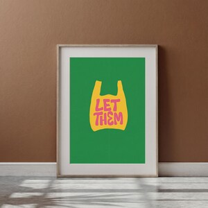 May include: Framed art print with a yellow plastic bag design on a bright green backdrop. The pink text reads "LET THEM". The artwork is displayed on a brown wall, adding a touch of modern decor.