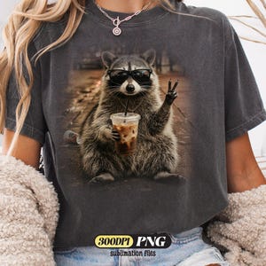 Funny raccoon wearing sunglasses holding iced coffee PNG design for sublimation