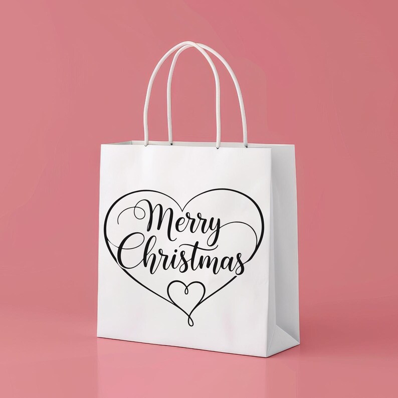 Op de afbeelding: Witte cadeauzak met een zwart hartvormig ontwerp en de woorden "Merry Christmas" in elegant schrift. De tas heeft witte handvatten en staat tegen een roze achtergrond, perfect voor kerstcadeaus.