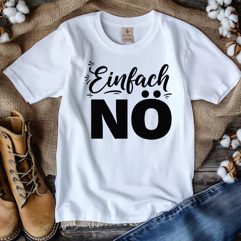 Puede incluir: Camiseta blanca con la frase alemana "Einfach N&Ouml;" impresa en negro. La camiseta tiene cuello redondo y mangas cortas. El texto est&aacute; en negrita, con fuente sans-serif. La camiseta se muestra sobre una superficie texturizada.