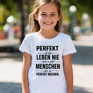 Puede incluir: Una camiseta blanca con texto negro. El texto dice: "PERFEKT ist das LEBEN NIE aber es gibt MENSCHEN die es PERFEKT MACHEN."