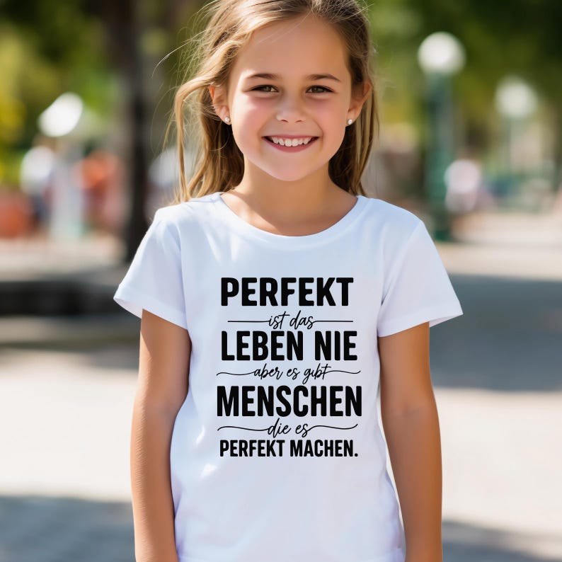 Puede incluir: Una camiseta blanca con texto negro. El texto dice: "PERFEKT ist das LEBEN NIE aber es gibt MENSCHEN die es PERFEKT MACHEN."