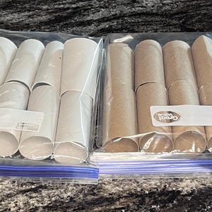 Könnte beinhalten: Zwei transparente Plastiktüten gefüllt mit Pappröhren. Eine Tüte enthält weiße Röhren, die andere braune Röhren. Jede Tüte hat ein weißes Etikett. Die Tüten liegen auf einer gesprenkelten grauen Oberfläche.