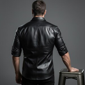 May include: Black leather shirt with a classic collar and buttoned cuffs. The shirt has a tailored fit and is made of a smooth, shiny material. The sleeves are rolled up to the elbows. The shirt is worn by a person.
