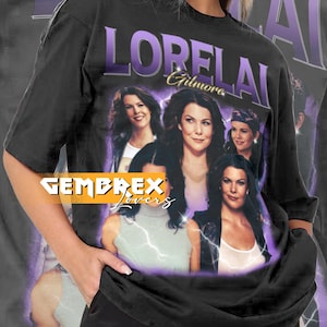 May include: Black unisex t-shirt featuring a graphic of Lorelai Gilmore with the text "LORELAI Gilmore". The shirt has a vintage style design with a purple and white color scheme. The brand name "GEMBREX Lovers" is also visible.
