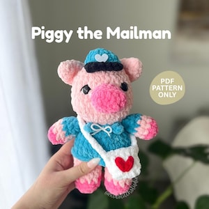 Op de afbeelding: Een handgemaakt, gehaakt varkentje verkleed als postbode. Het varkentje is roze en blauw, met een witte postzak met een rood hart. De tekst "Piggy the Mailman" wordt boven het varkentje weergegeven. De woorden "PDF Pattern Only" zijn ook zichtbaar.