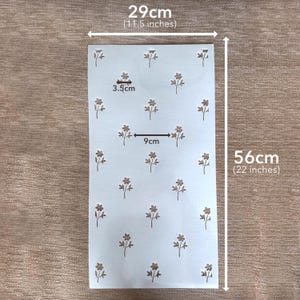 Puede incluir: Una hoja de plantilla rectangular blanca con un patr&oacute;n repetitivo de peque&ntilde;as flores marrones. La hoja mide 29 cm de ancho por 56 cm de alto. Los motivos florales individuales miden 3,5 cm de ancho, con un espacio de 9 cm entre elementos.